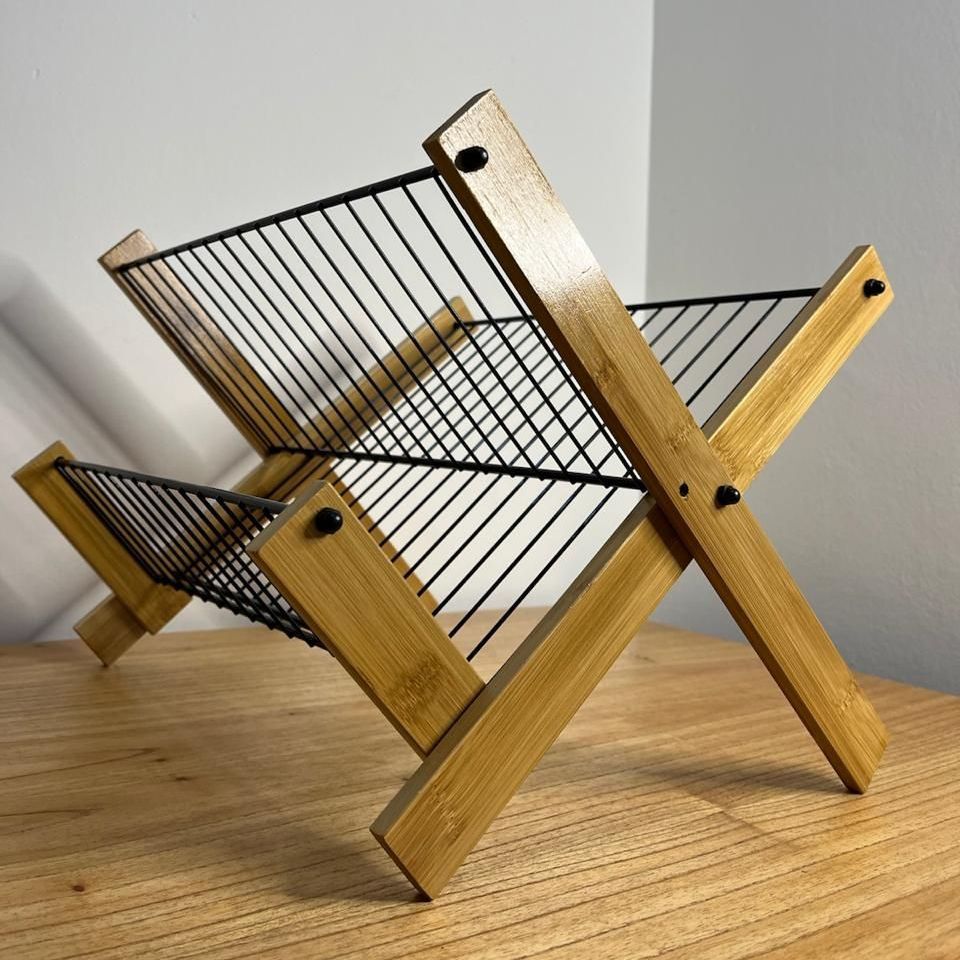 Un escurreplatos de madera con una cesta de alambre negra encima.