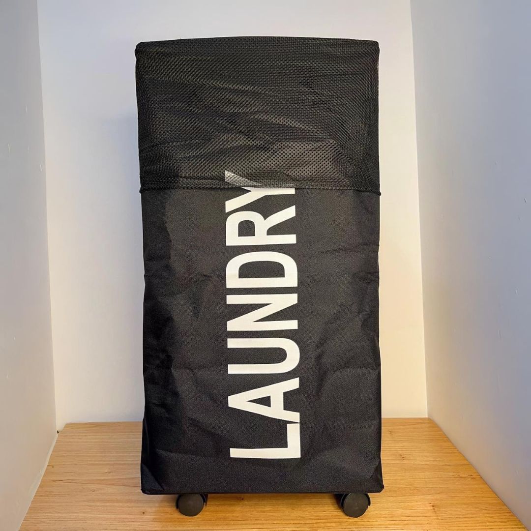 Una bolsa de lavandería negra está sobre una mesa de madera.