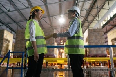 Um homem e uma mulher apertam as mãos em um armazém.