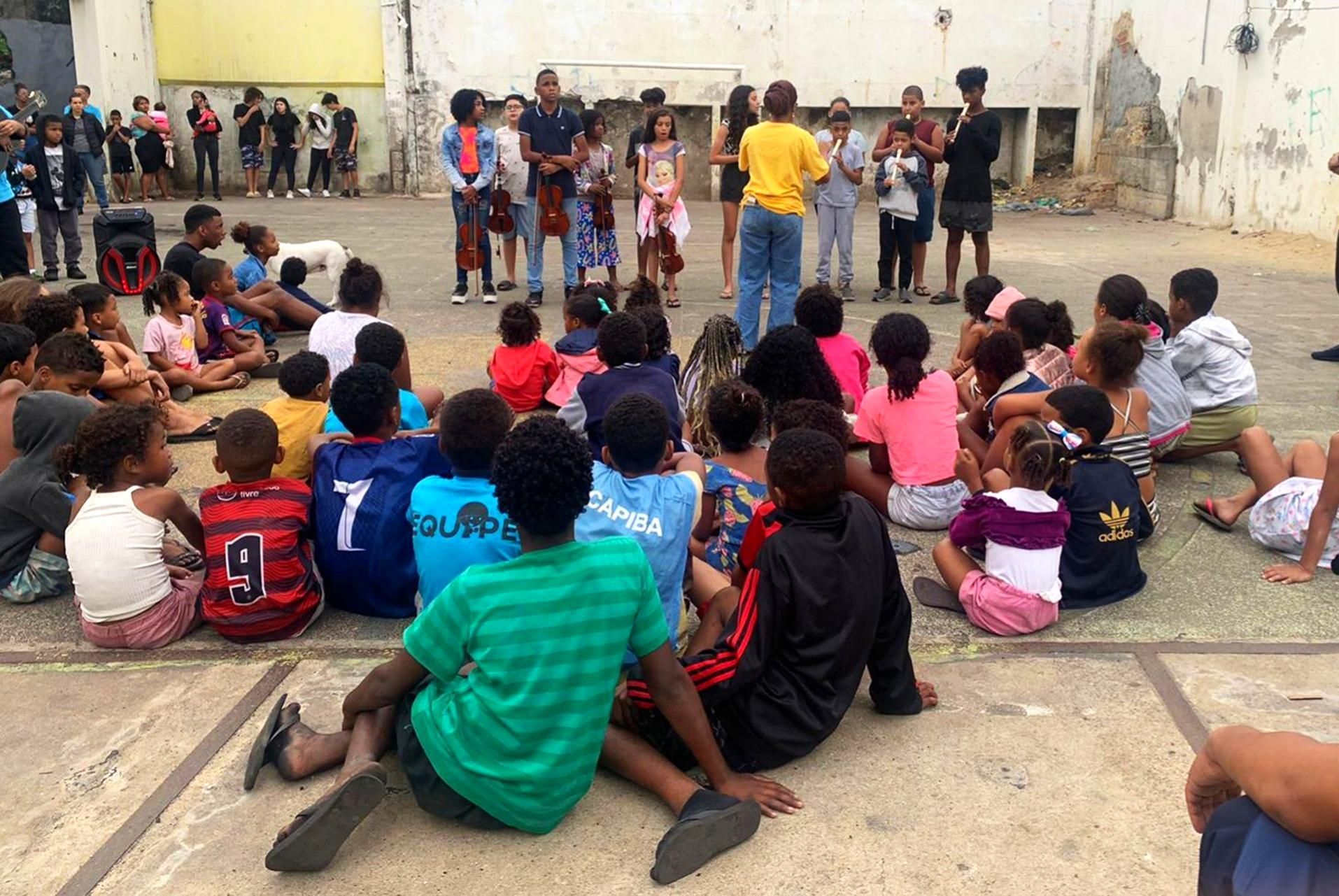 Um grupo de crianças está sentado no chão em círculo.