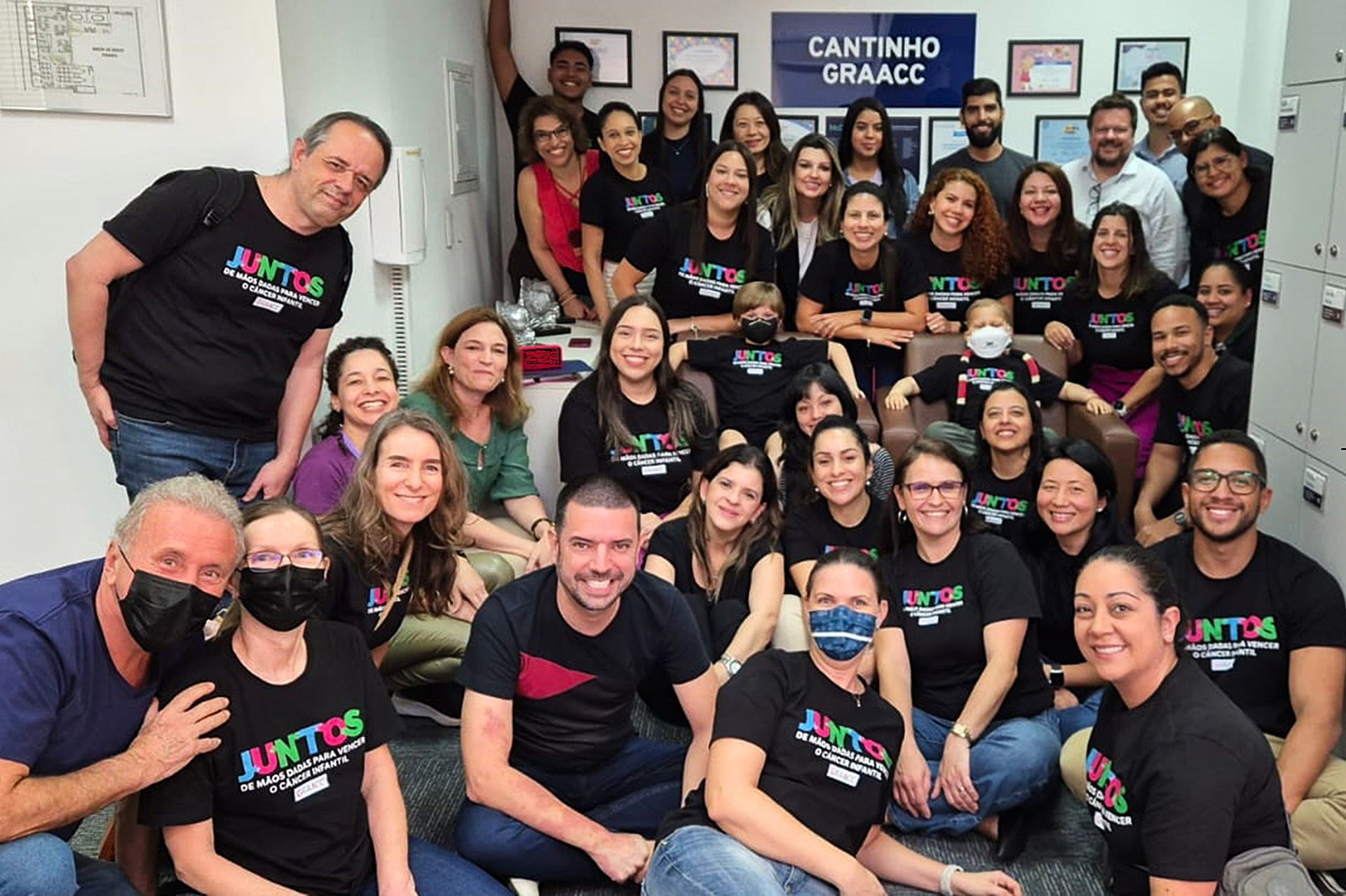 Um grande grupo de pessoas está posando para uma foto em uma sala.