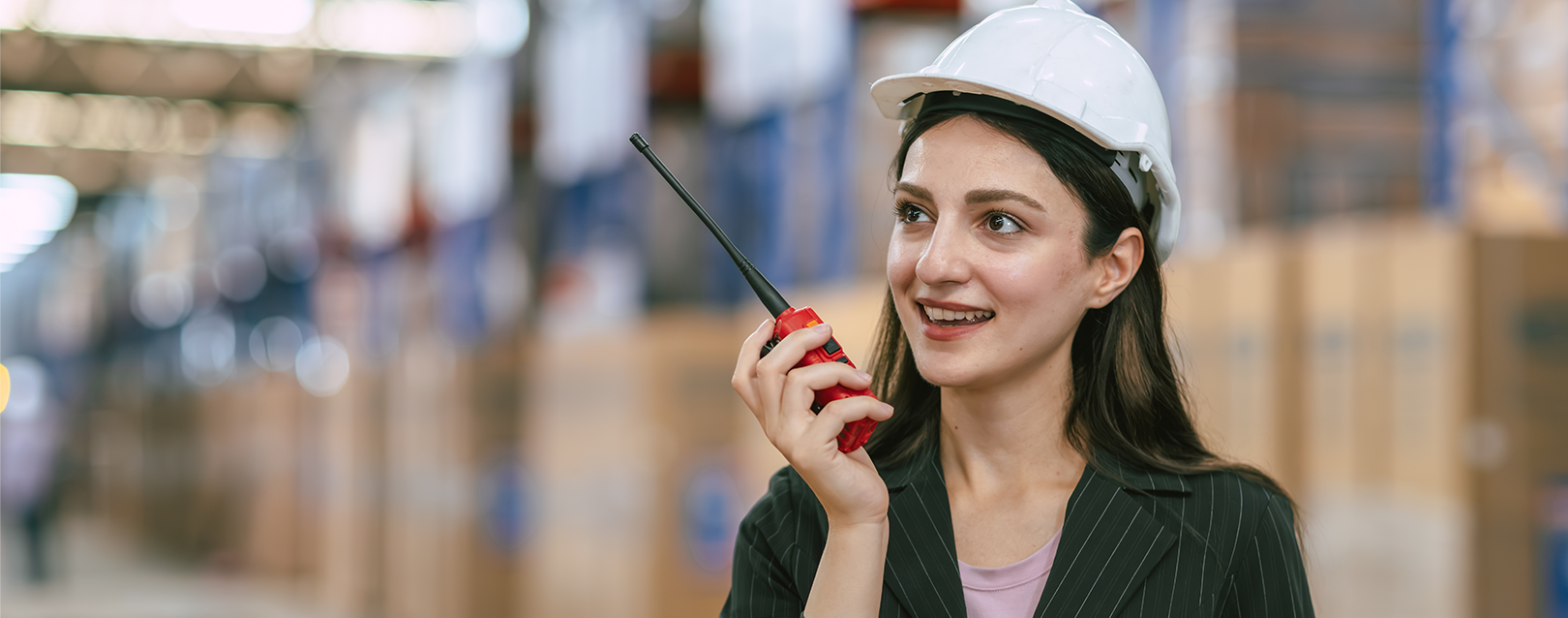 Operador logístico com rádio em armazém repleto de prateleiras com carga LCL.
