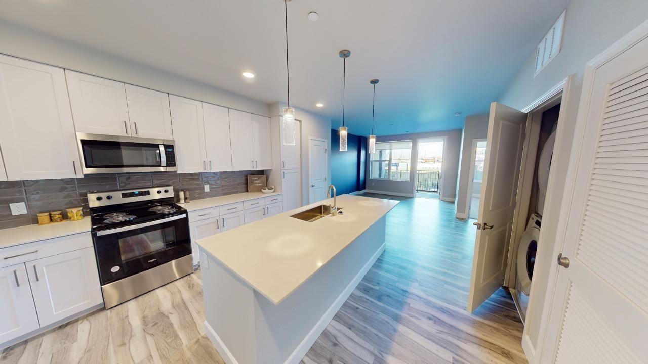 A kitchen with white cabinets, stainless steel appliances, and a large island.