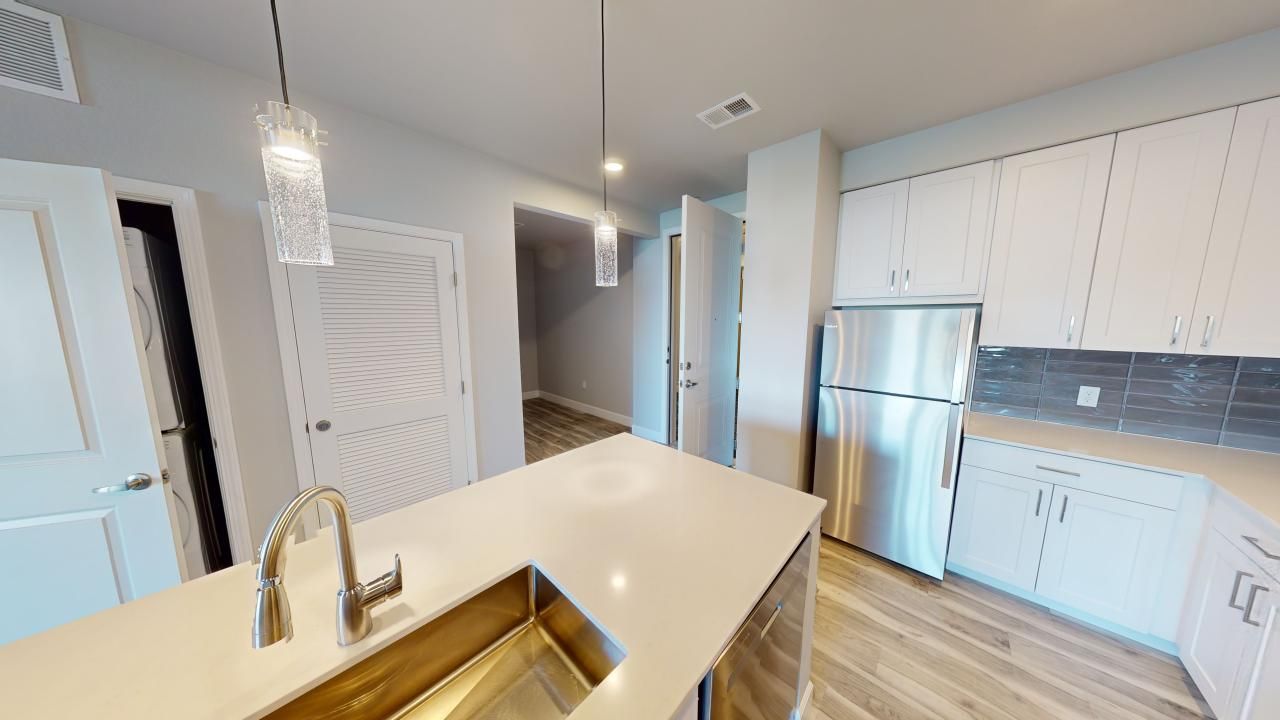 A kitchen with a sink, refrigerator, and cabinets.
