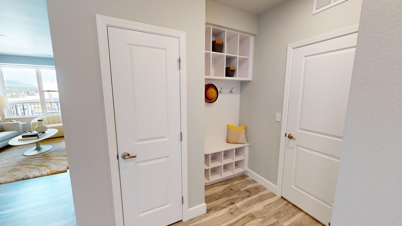 A hallway in a house with white doors and a shoe rack.