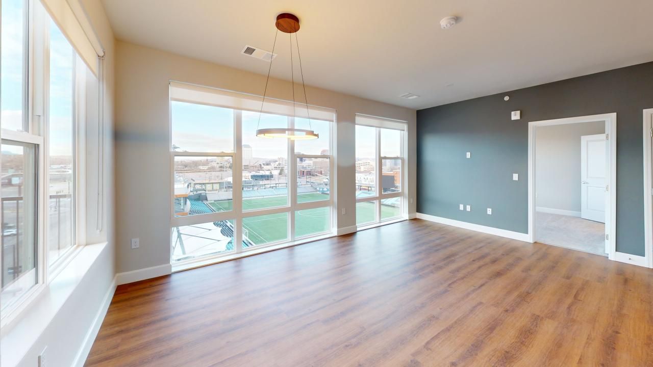 An empty living room with hardwood floors and lots of windows.