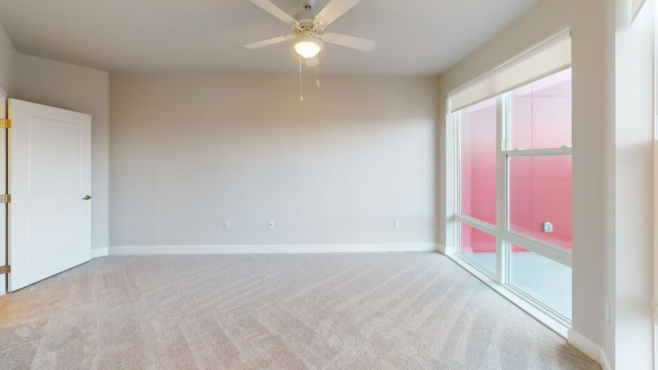 An empty room with a ceiling fan and a large window.