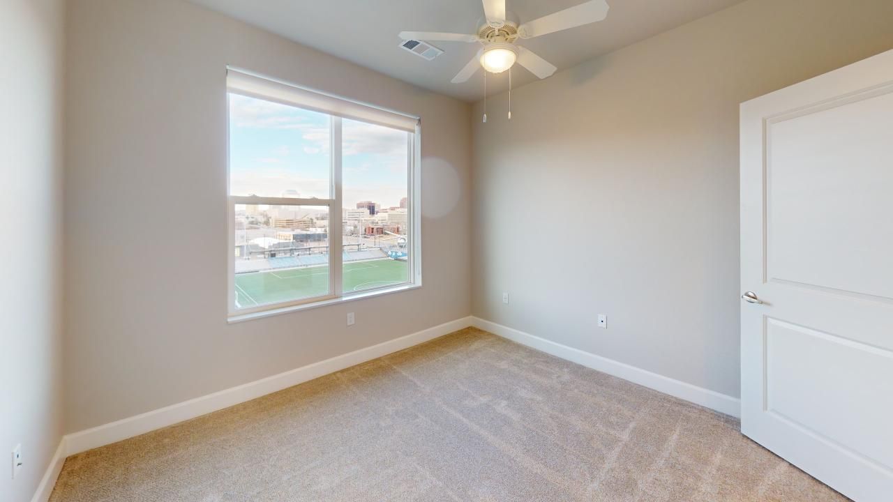 An empty bedroom with a ceiling fan and a window.