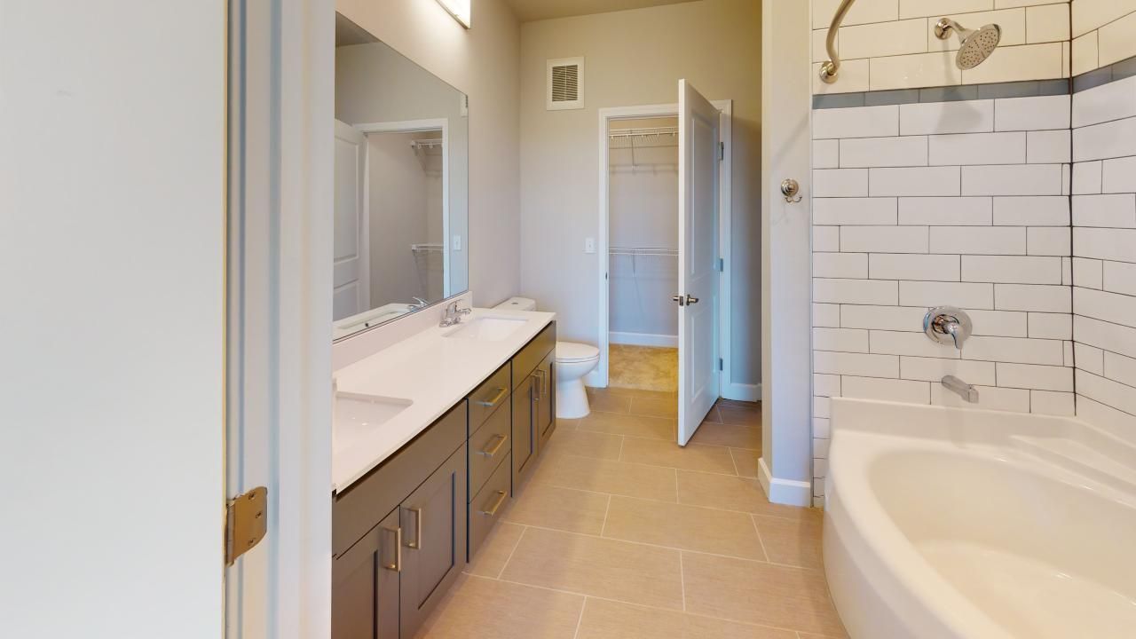 A bathroom with a tub, sink, toilet and shower.
