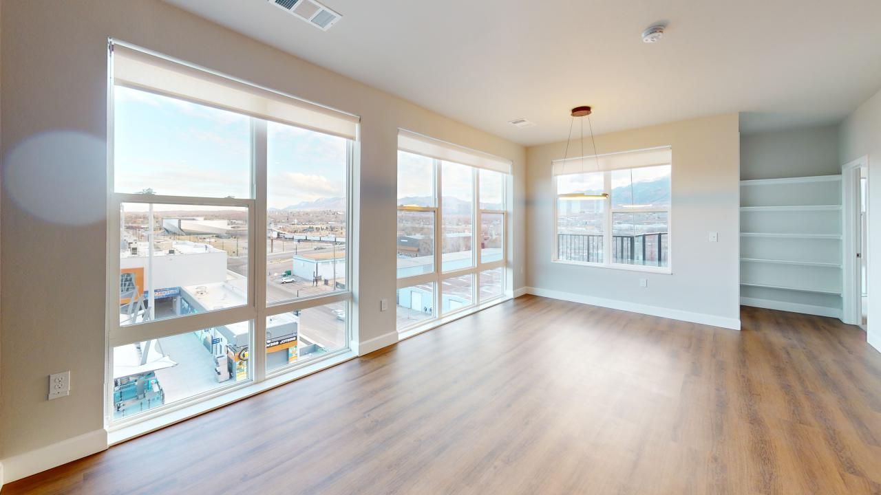 An empty living room with hardwood floors and lots of windows.