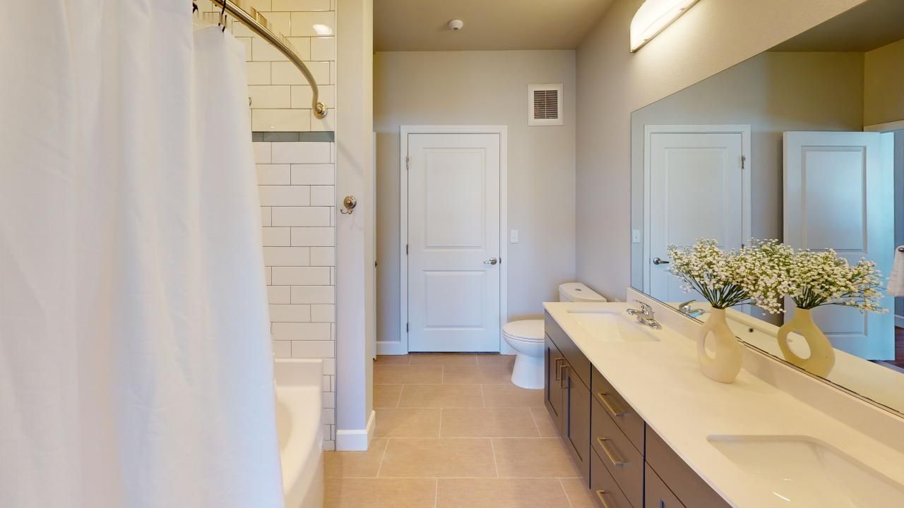 A bathroom with two sinks, a toilet, and a large mirror.