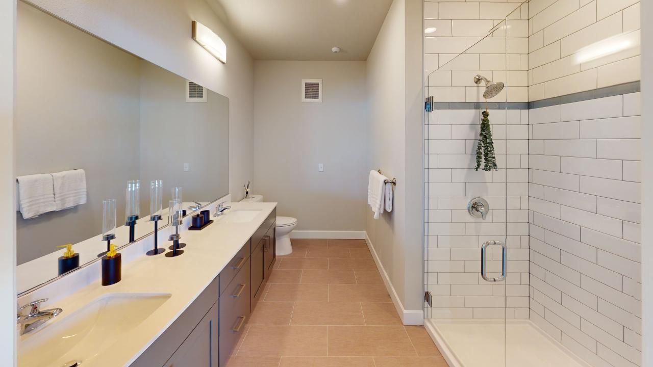 A bathroom with two sinks, a toilet, and a walk-in shower.