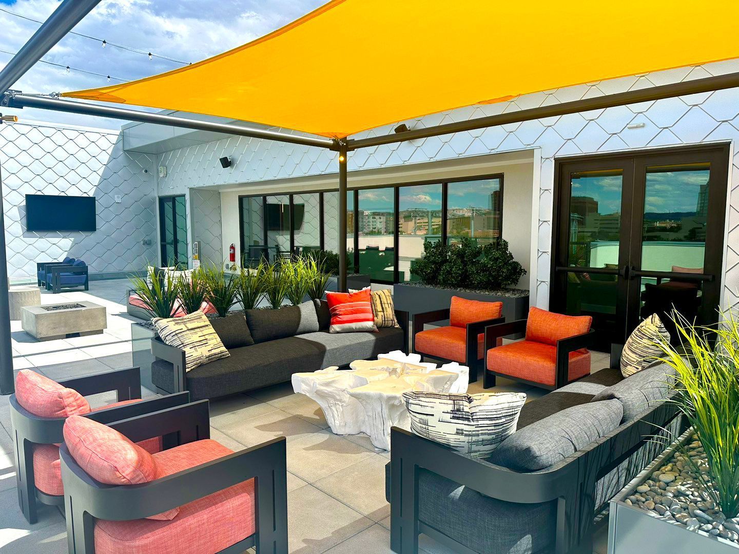 A patio with a lot of furniture and a yellow umbrella.