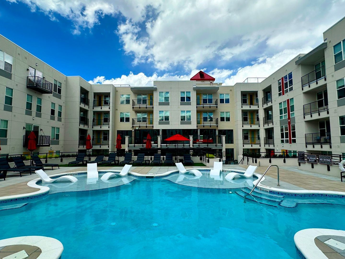 A large swimming pool in front of a large apartment building.
