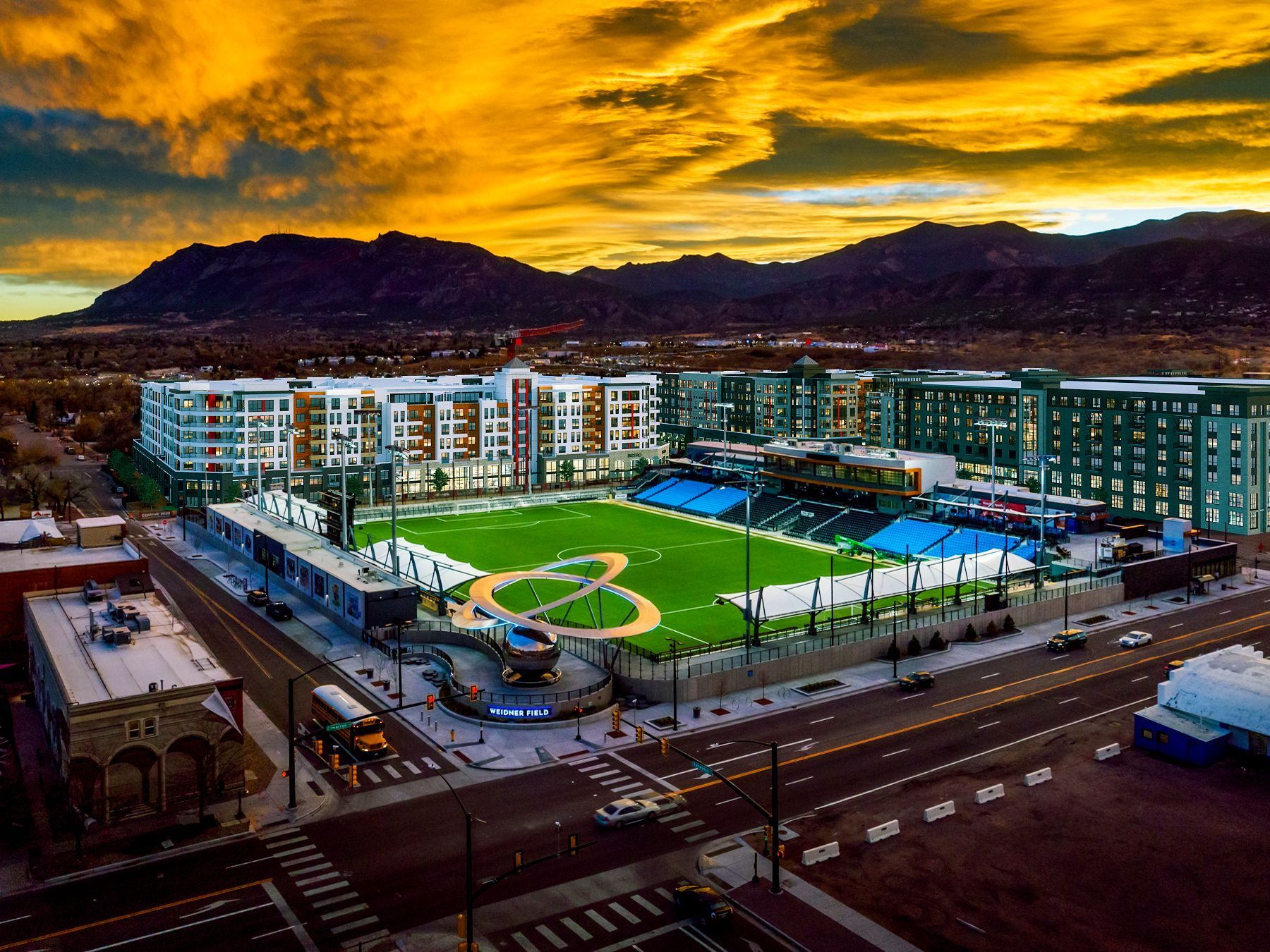An aerial view of a baseball field in a city at sunset.