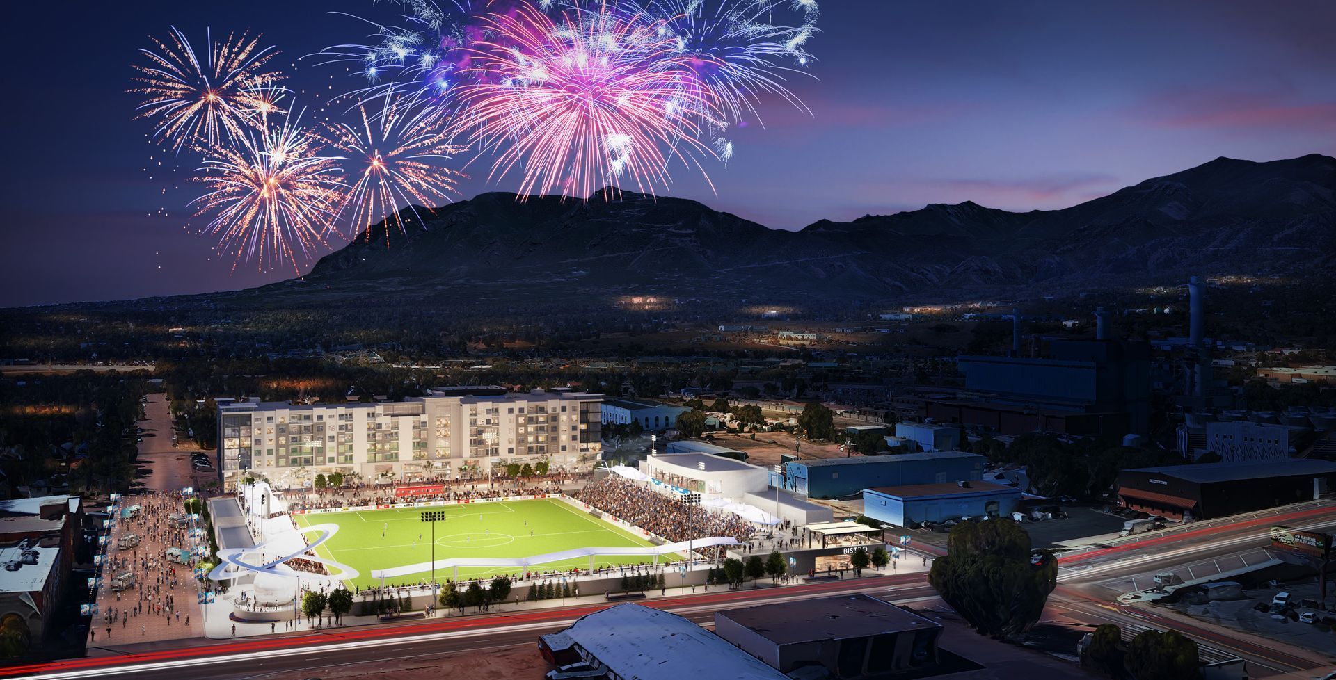 An aerial view of a stadium with fireworks going off in the background.
