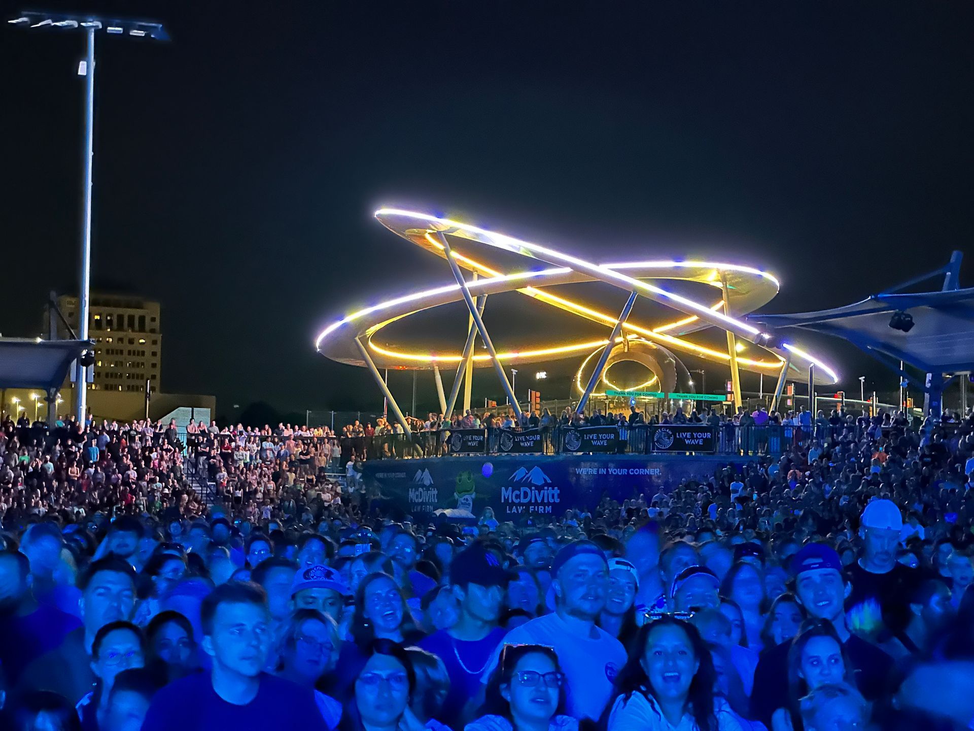 A crowd of people at a concert with a ferris wheel in the background at The Experience at Epicenter