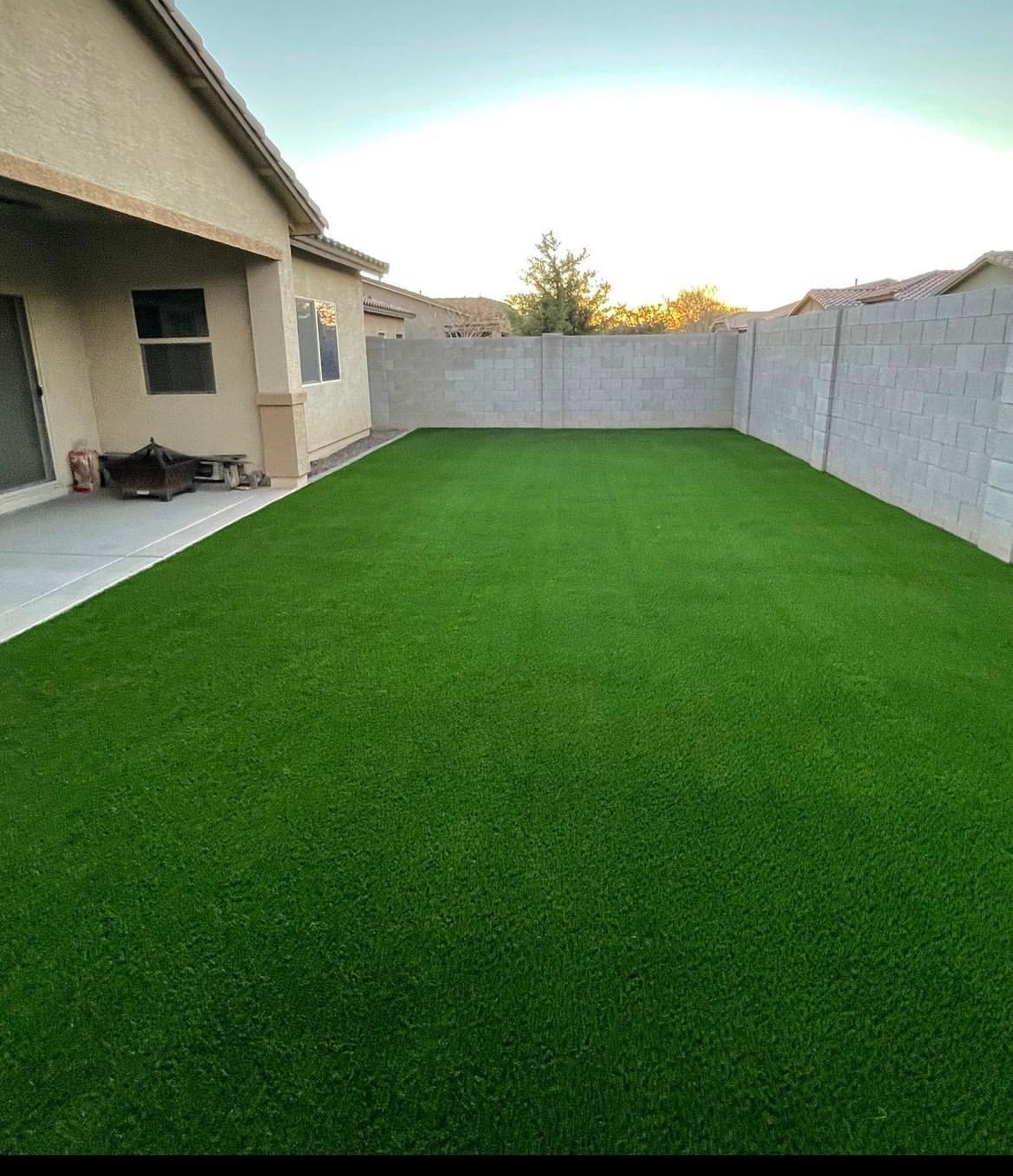 A backyard with a lot of green grass and a house in the background.