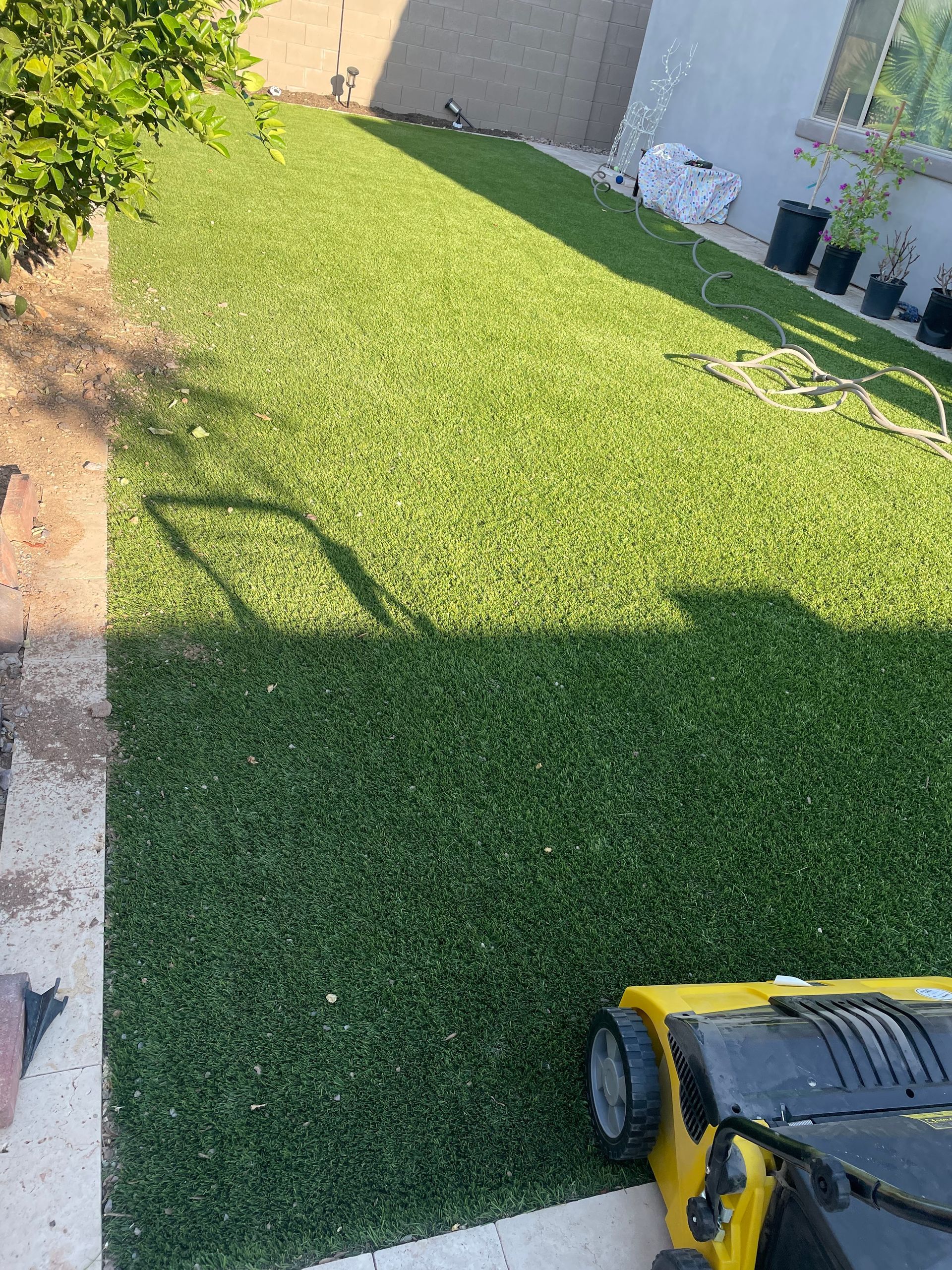 A yellow lawn mower is sitting on top of a lush green lawn.