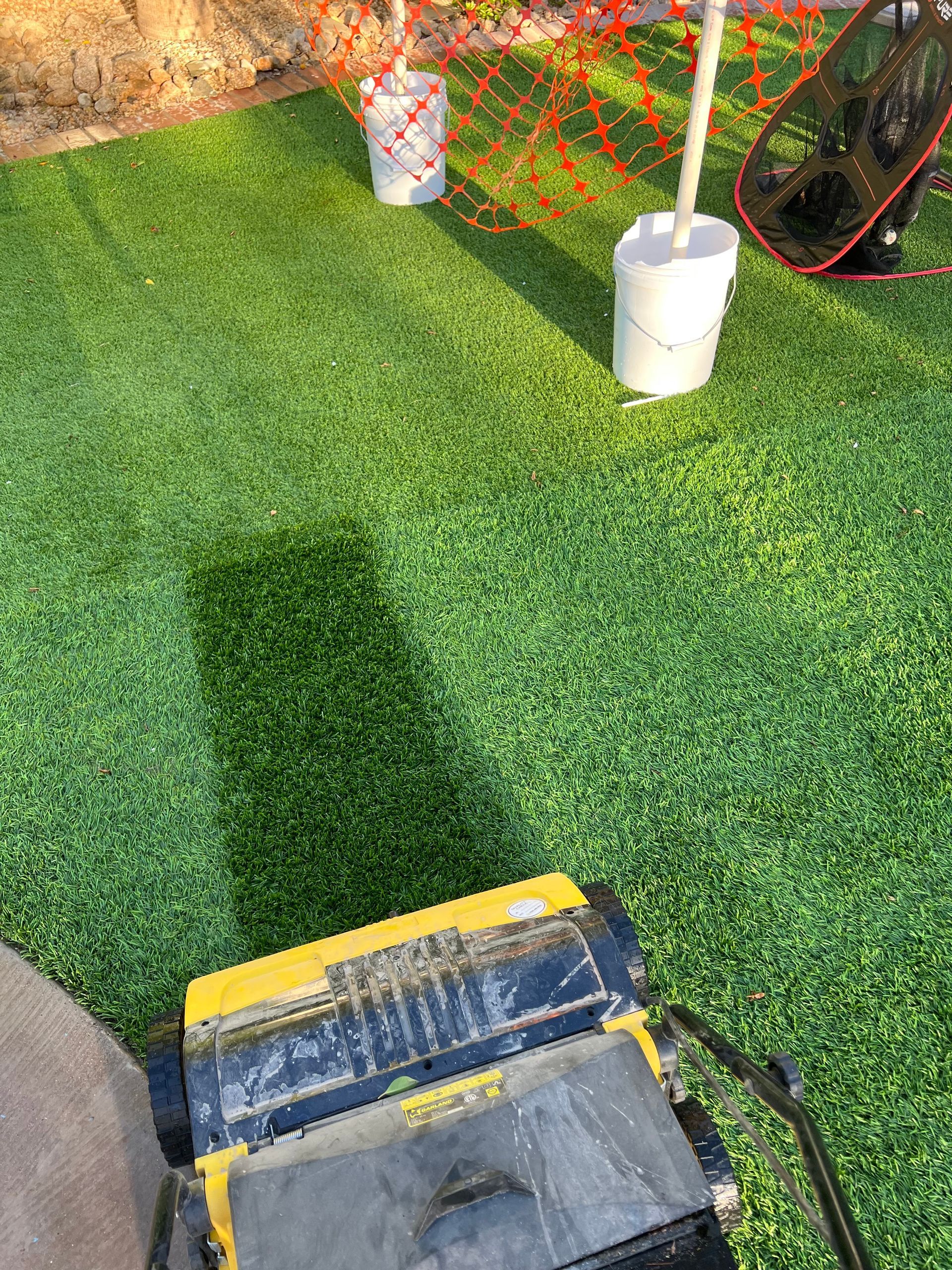 A yellow and black machine is sitting on top of a lush green lawn.