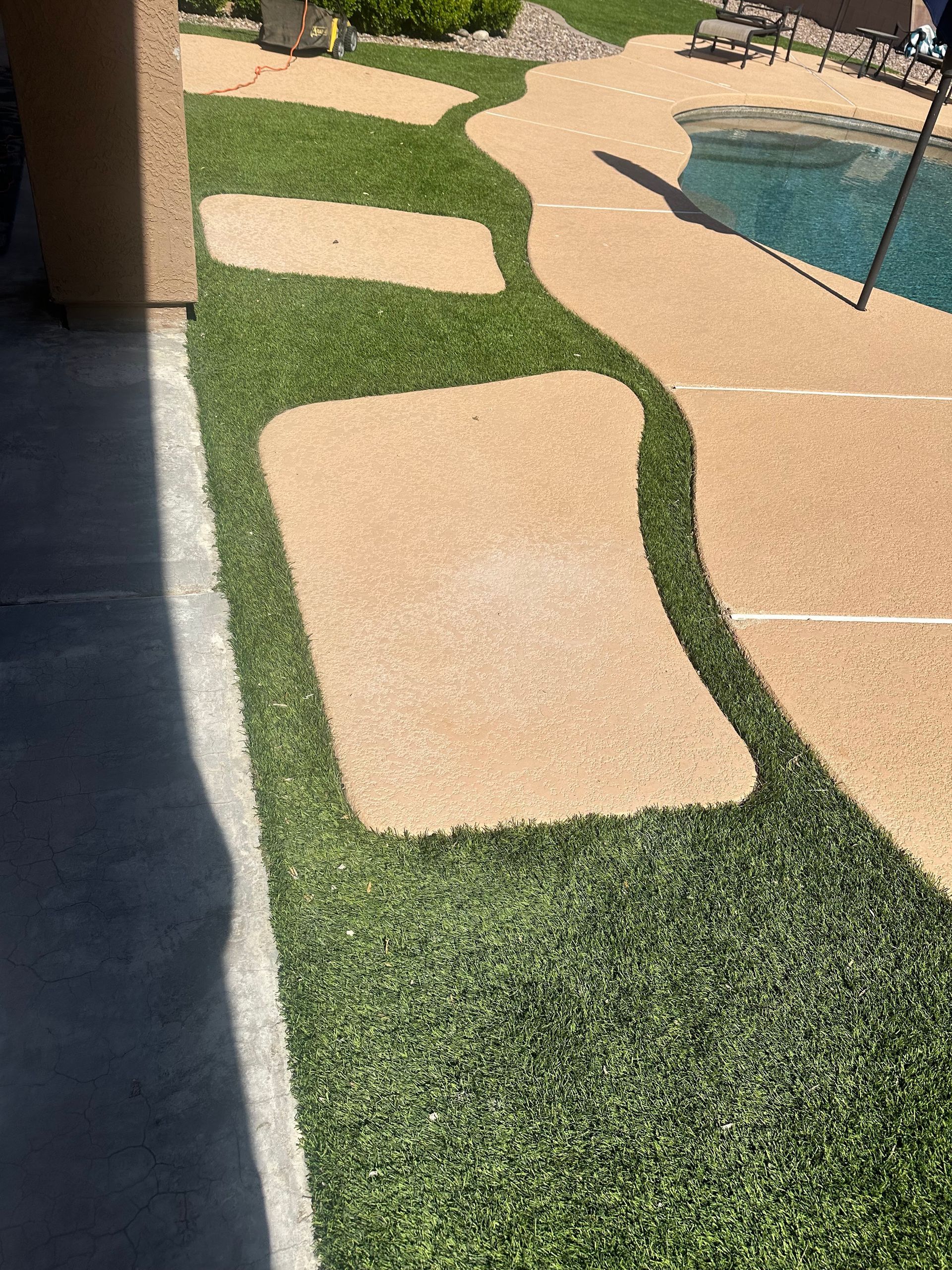 A lawn with a concrete walkway leading to a pool.