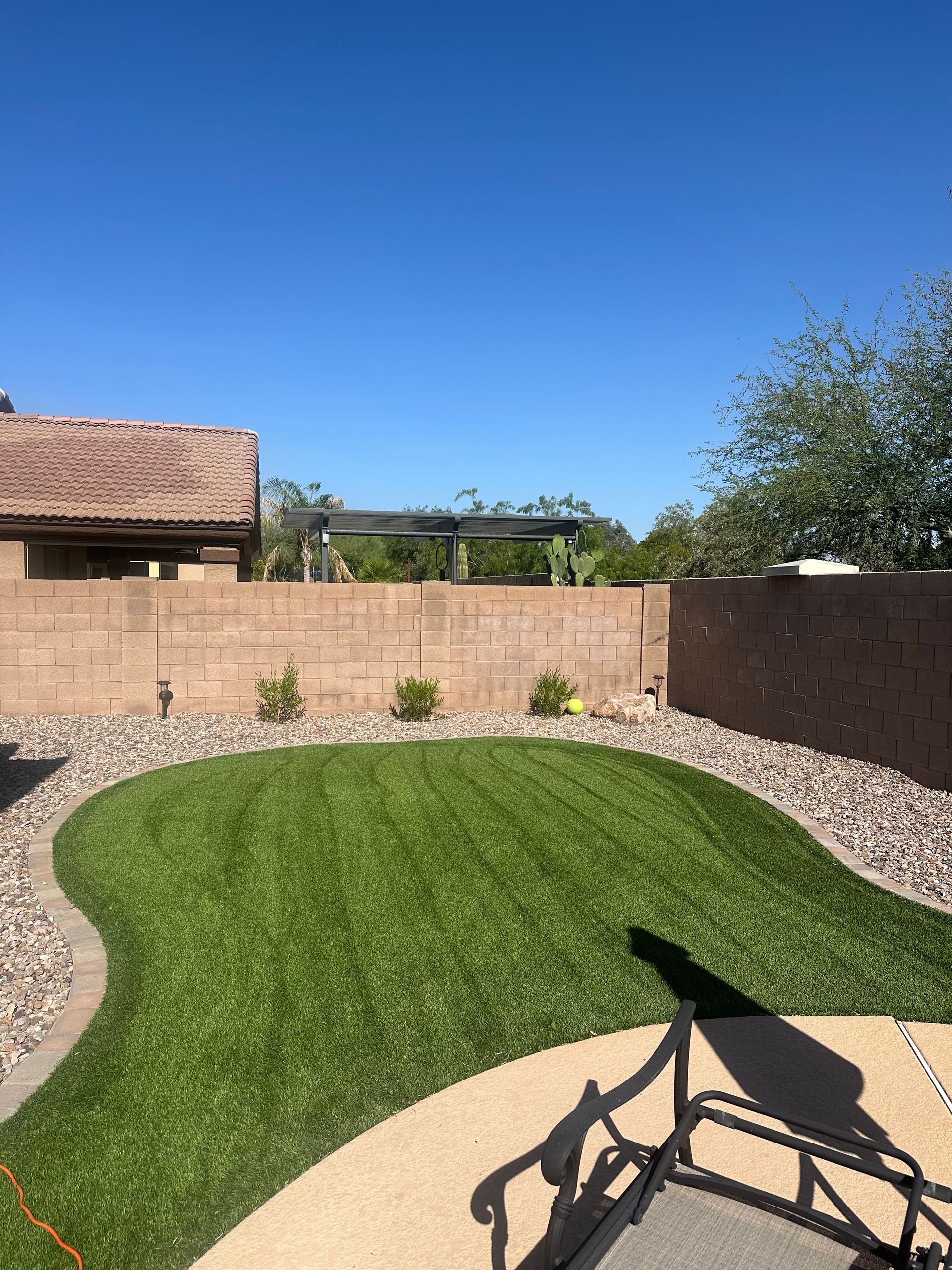 A backyard with a lush green lawn and a brick wall.