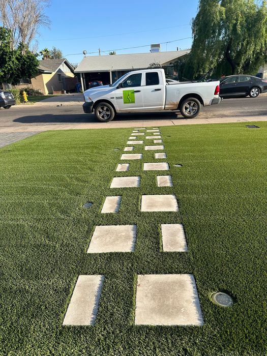 A white truck is parked in the grass in front of a house.