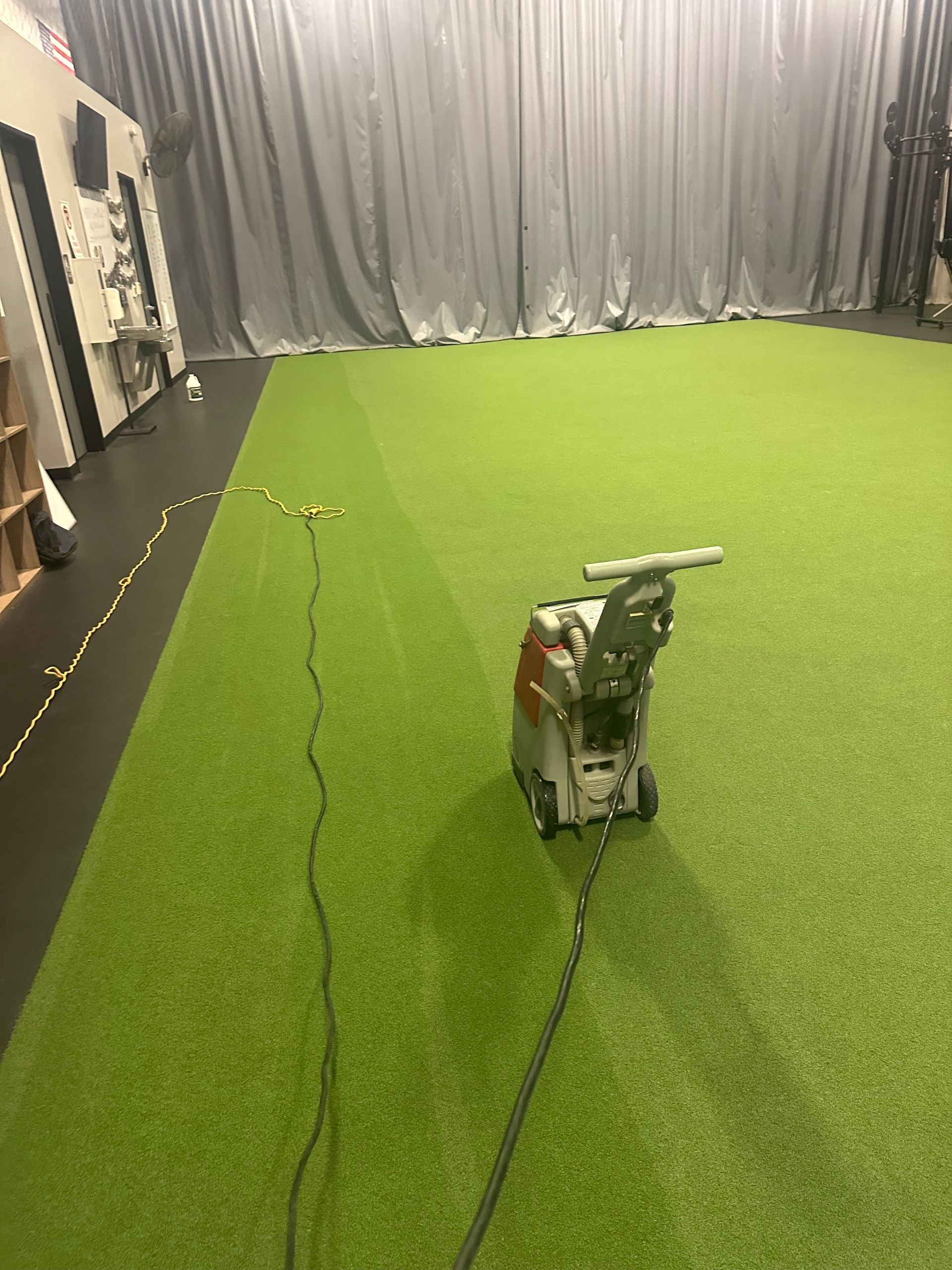 A vacuum cleaner is sitting on top of a green carpet in a room.