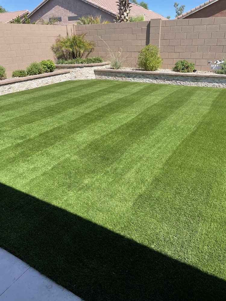 A backyard with a lush green lawn and a brick wall.