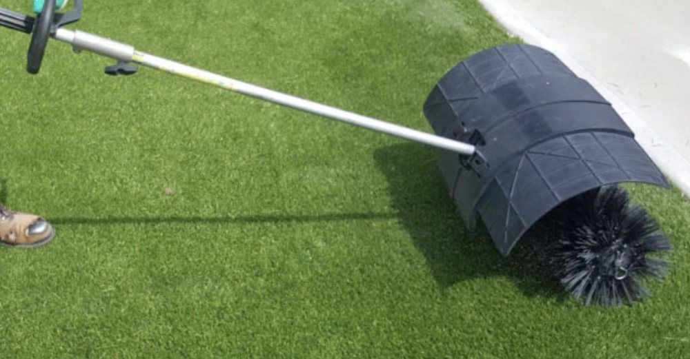 A person is using a broom to clean a lawn.
