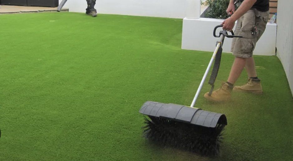 A man is sweeping the grass with a broom.