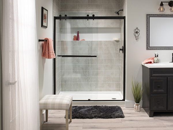 Close-up detail view of a sliding glass shower door enclosure with chrome framing and clear glass panels. The interior shows