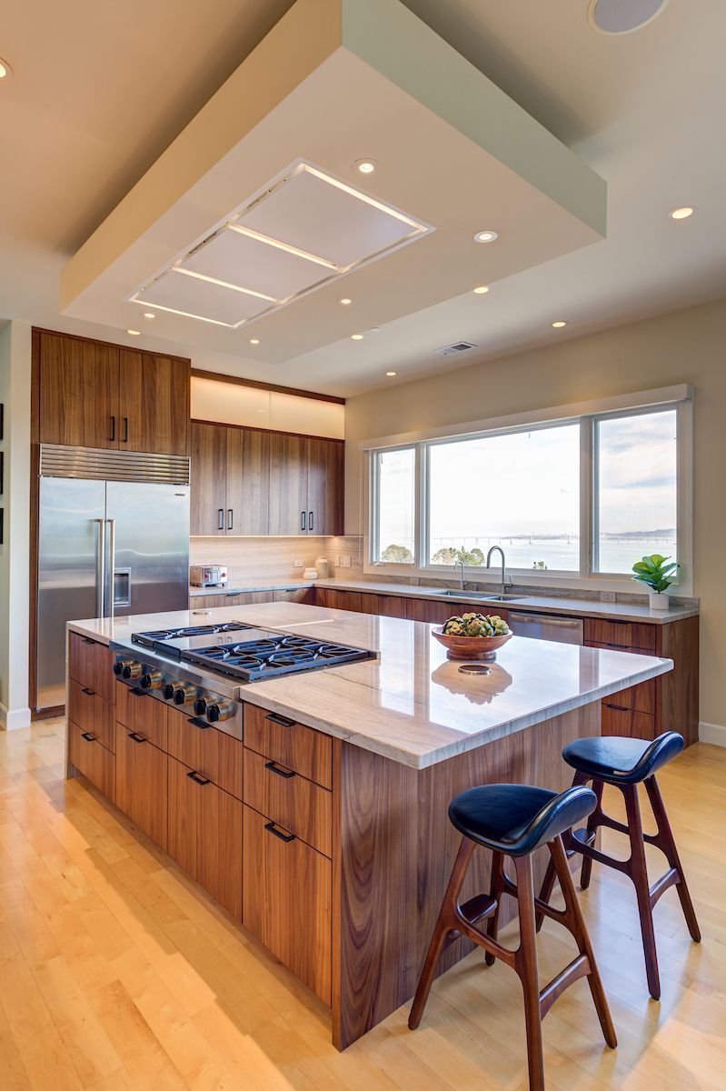 Luxurious kitchen with rich warm wood-grain cabinetry on island and lower cabinets, paired with...]