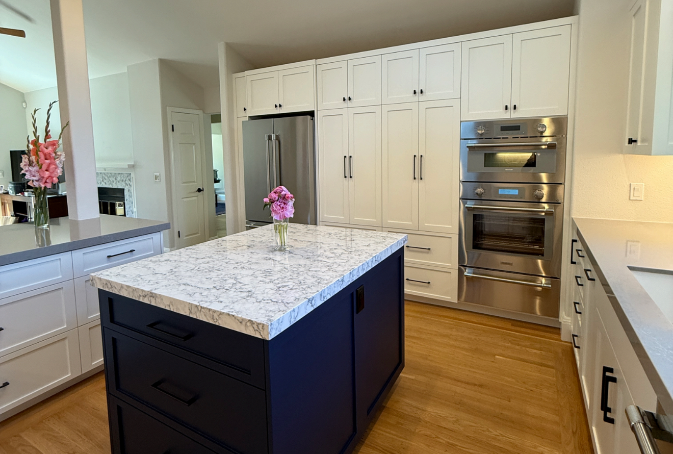 Transitional kitchen with cream-colored flat-panel cabinetry and a contrasting navy blue island...]