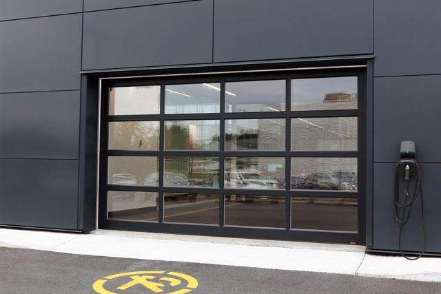 Black storefront with large glass window and door; yellow accessibility symbol painted on the pavement.