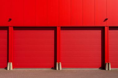Row of bright red garage doors on a red industrial building facade