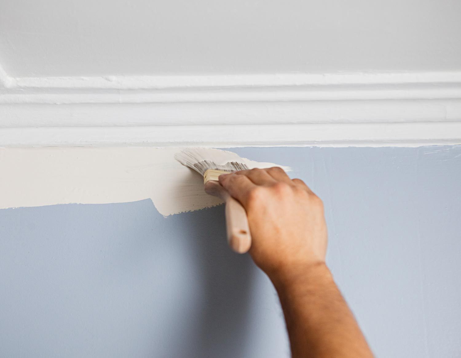 A person is painting a piece of wood with a brush.