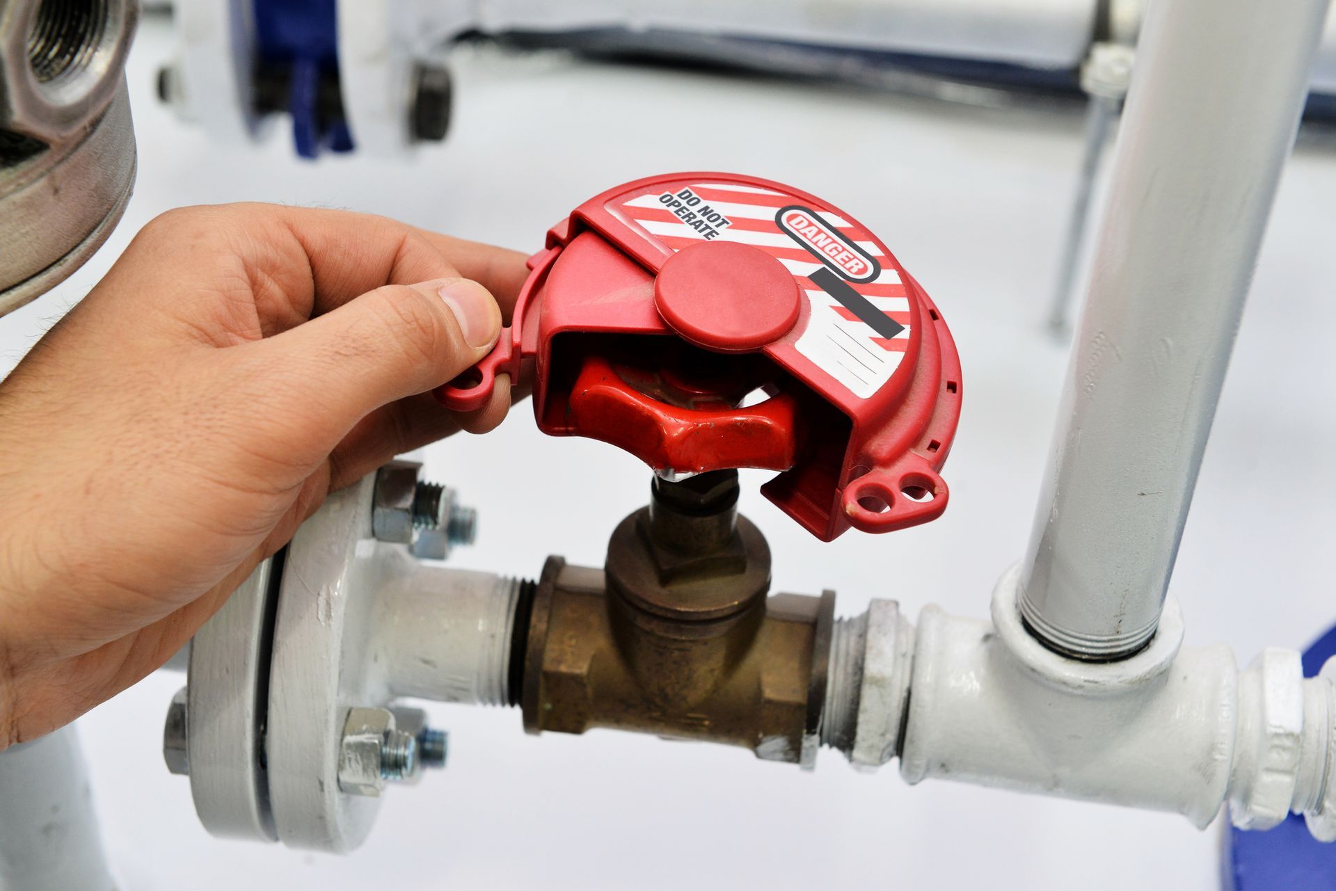 A person is holding a red valve on a pipe.