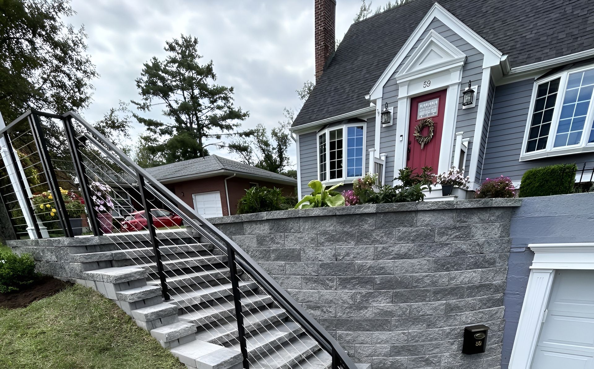 Gray house with stone stairs and black railing leading up to the front door.