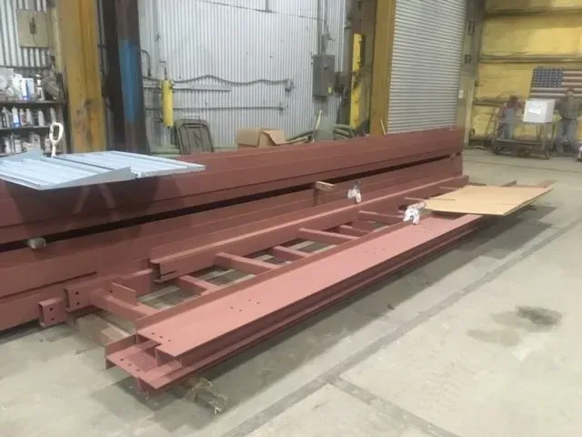 Red steel beams and metal sheets in a warehouse, possibly for construction.