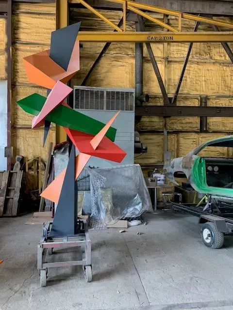 Abstract sculpture of colorful geometric shapes in a workshop setting.