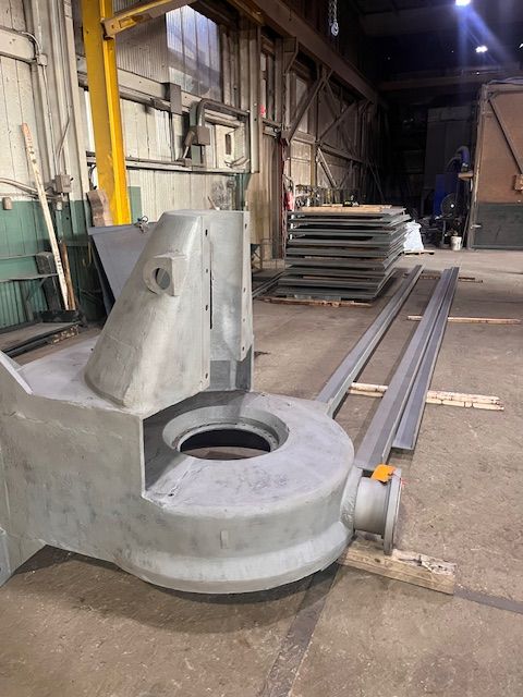 Large industrial machine component with cylindrical opening, metal beams, factory setting.