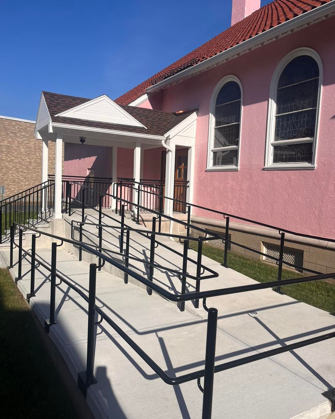 Pink building with wheelchair ramp and black handrails.