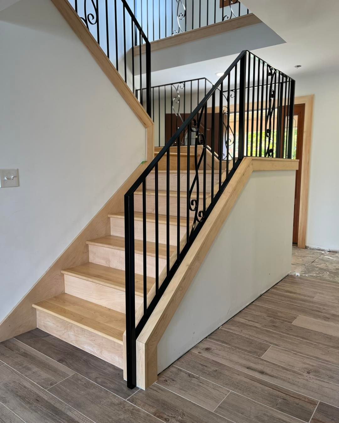 Black decorative metal fence in front of a white house with a driveway. A purple umbrella is visible.