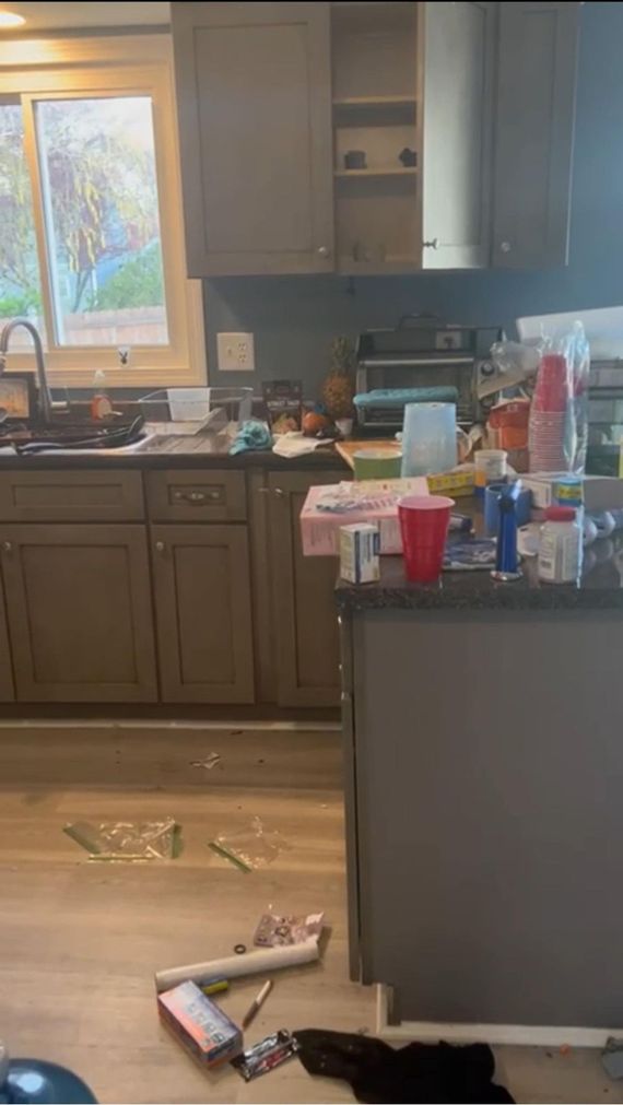 A kitchen with a lot of junk on the floor and counters.