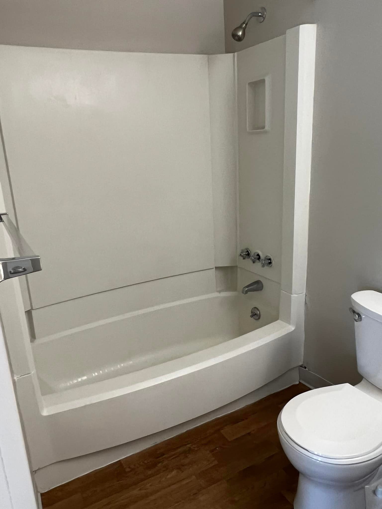 A bathroom with a toilet , bathtub and shower.