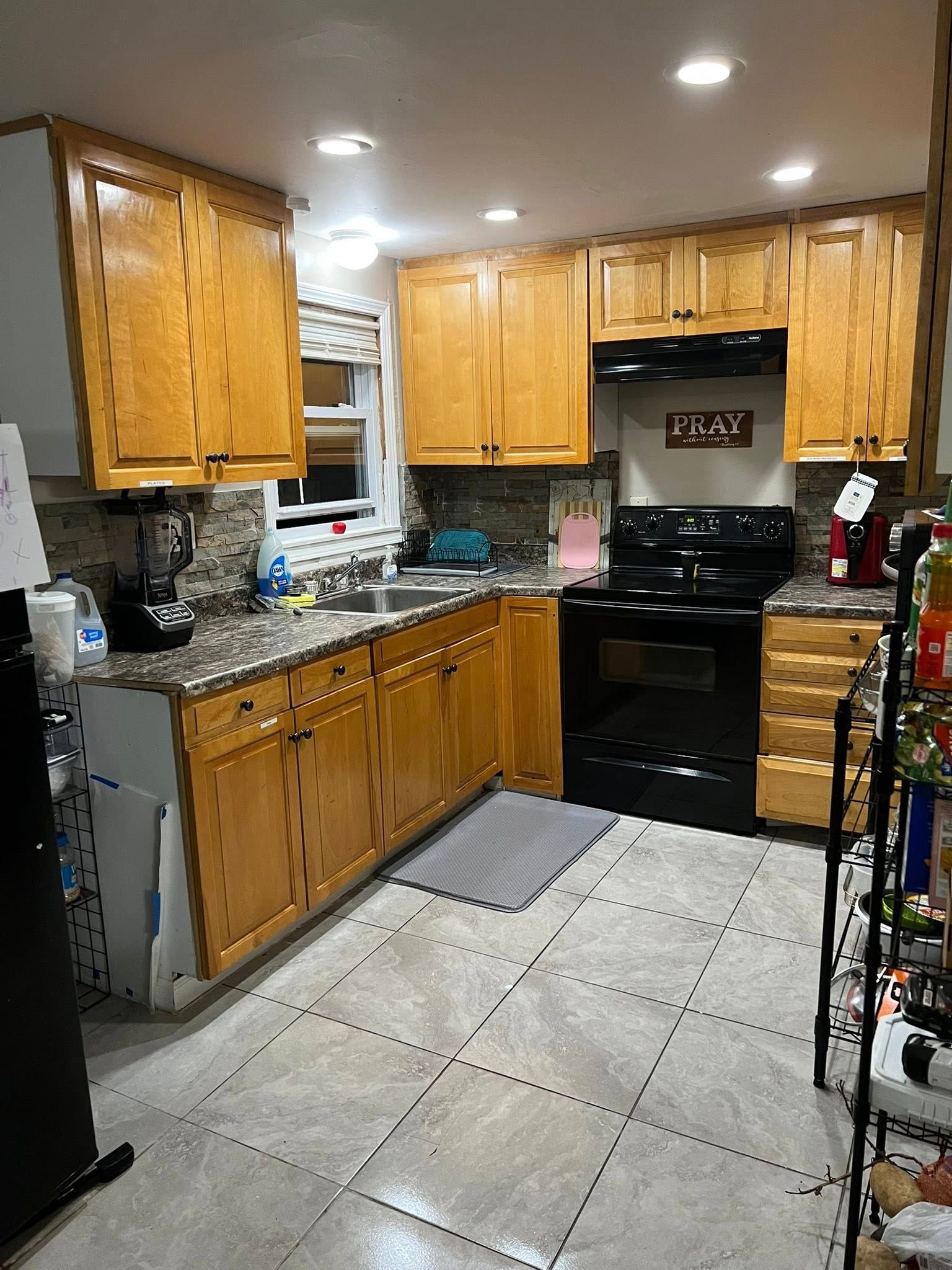 A kitchen with wooden cabinets , granite counter tops , a stove and a sink.