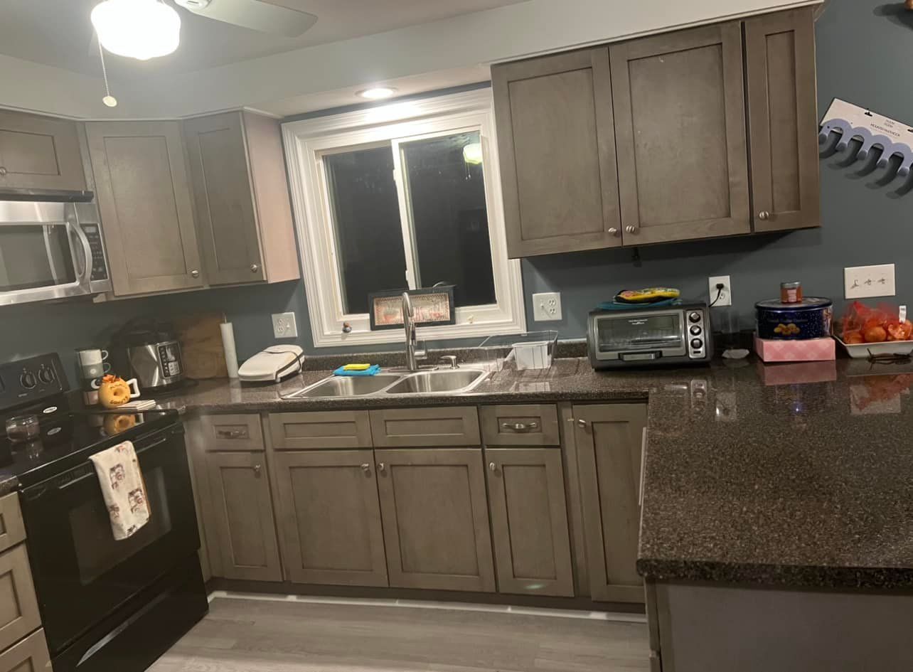 A kitchen with a sink , stove , microwave , and a window.