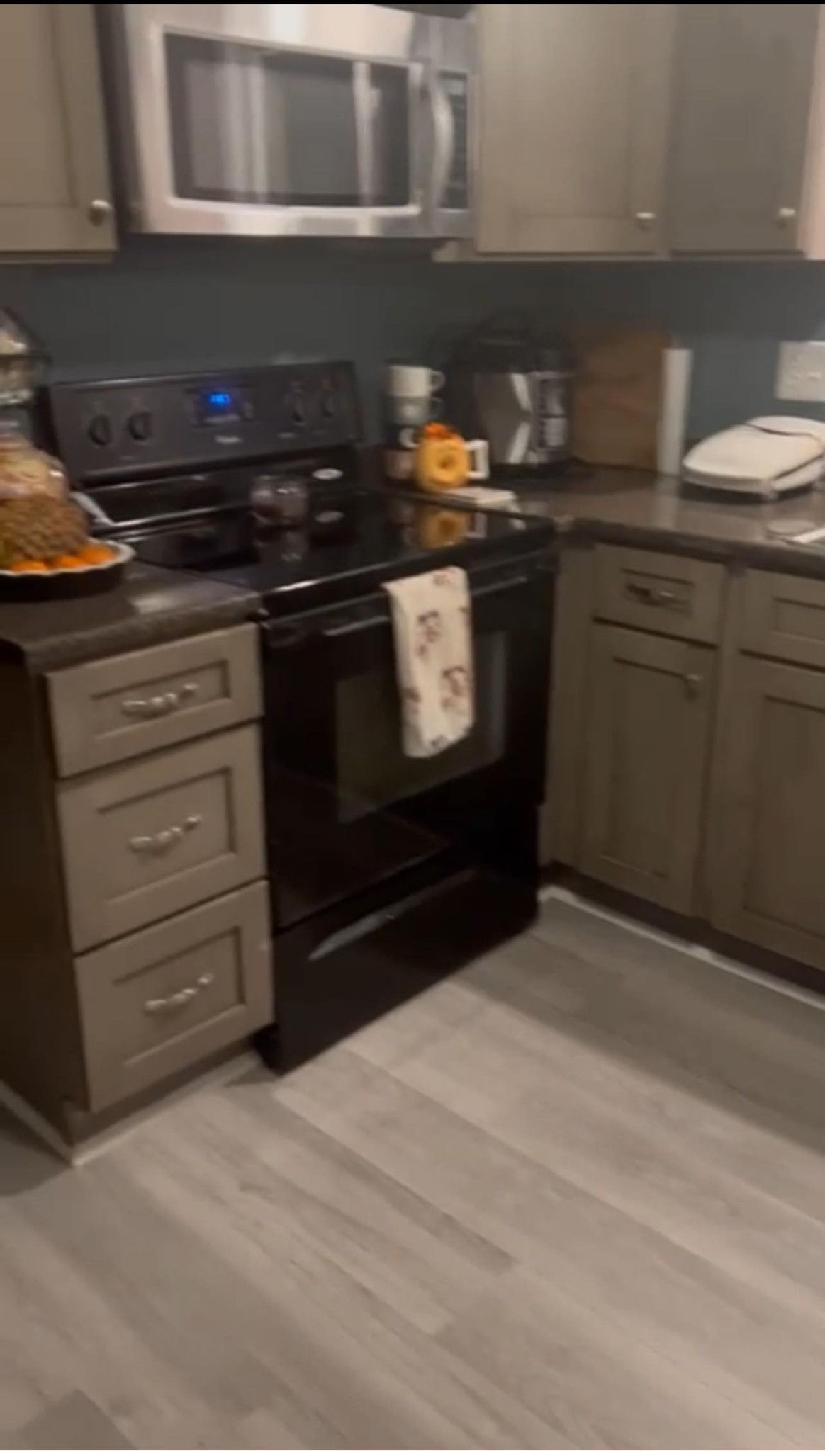 A kitchen with a stove , microwave , sink and cabinets.