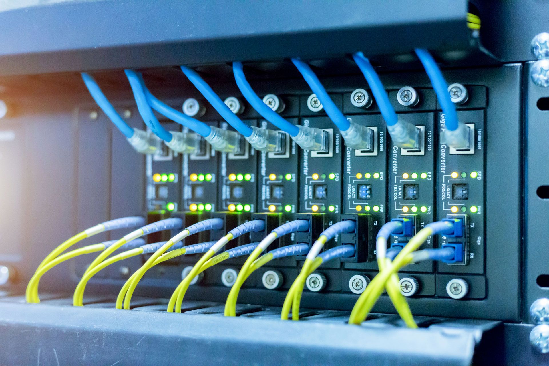 Network server rack with blue and yellow Ethernet cables plugged into ports.